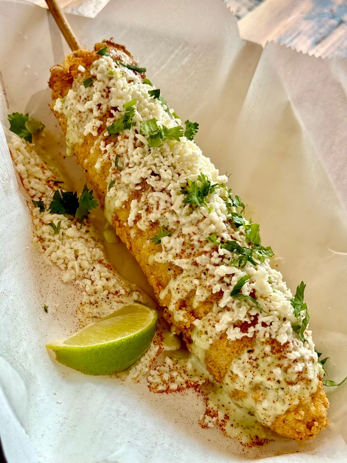 Mexican street corn (elote) on a stick with cotija, crema and chili